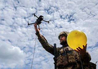 A Ukrainian serviceman lifts a drone attached to a balloon for target practice during anti-drone training at an undisclosed location near the frontline in the Kharkiv region, northeastern Ukraine